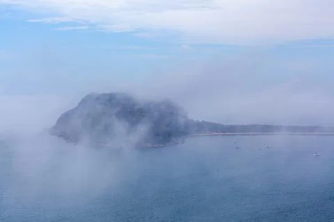 Low clouds above the ocean hiding moored sailboats and Barrenjoey lighthouse  Stock Photos