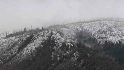 Low clouds are enveloping a snowy mountainside Видео 307103057