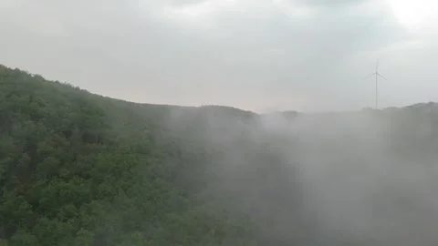 Low clouds drifting over forested Hunsrück ridge and wind farm 스톡 동영상 340367799