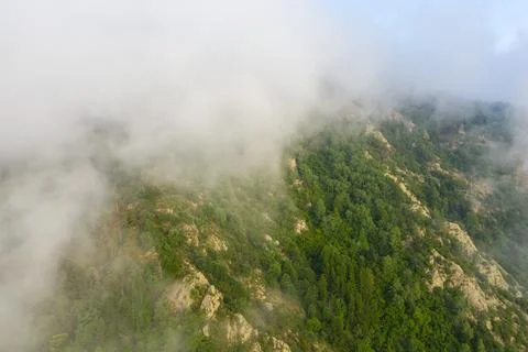 Low clouds drifting over rocky green hillside Stock Photos