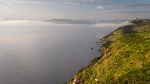 Low clouds forming and rolling over sea and coastline during early morning Stock Photos