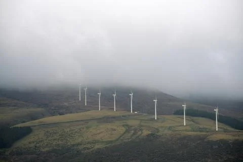 Low clouds hide the mountain peaks over a wind farm Stock Photos