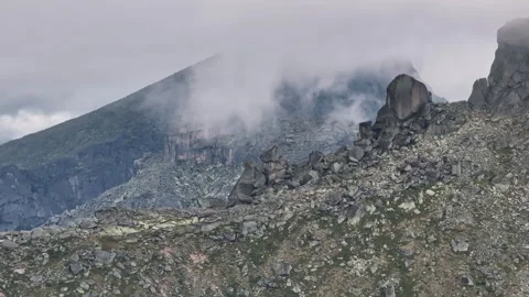 Low clouds moving over a rocky mountain peak Stock Footage 300931978