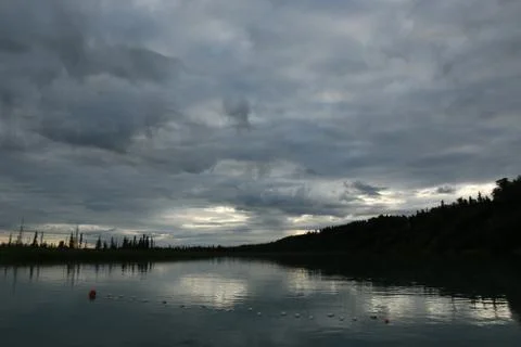 Low clouds overhang the river while a patch of sunlight peeks through. Stock Photos