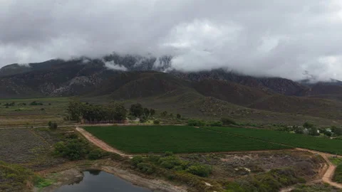 Low Clouds Rolling Over Mountain Range Above Farmland in Western Cape Stock Footage 330343222