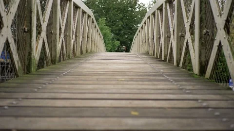 Low down shot looking down the length of a footbridge over a canal Video stock 117432688