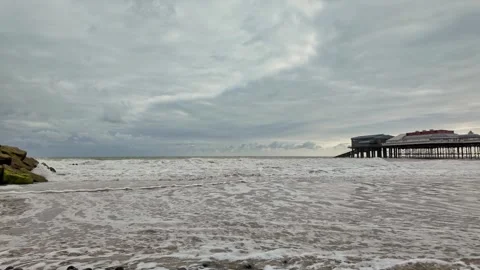 Low down slow motion pan across the beach as the tide rolls in Video stock 314221468
