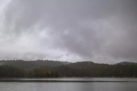 Low drifting clouds over calm alpine shoreline. Stock Photos