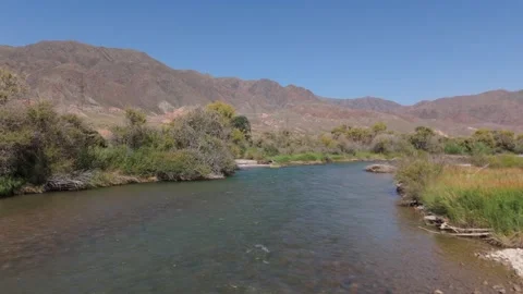 Low drone flight along a river toward red mountains, Kok-Moinok, Kyrgyzstan Video stock 347239843