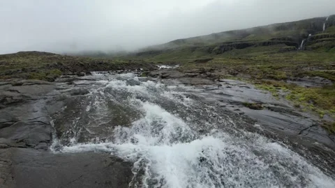 Low drone flight up mountain stream with small cascades, Reydarfjordur Iceland Stock Footage 346552245