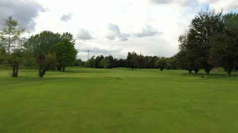 Low drone flight over freshly cut golf field lined with full-grown trees, 4K Stock-Footage 155816931
