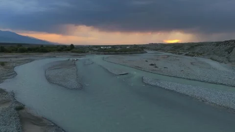 Low drone flight over a glacial river at stormy sunset, Kyrgyzstan Видео 347241139