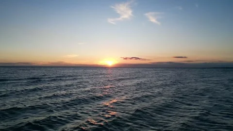 Low drone flight over the ocean at sunset, moving straight toward the sun. Stock Footage 326972967