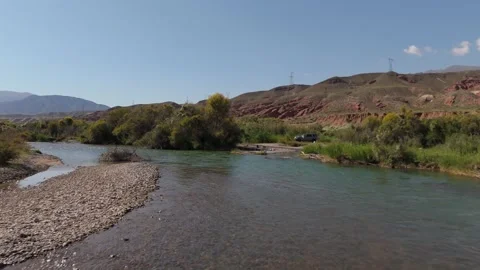 Low drone flight over a river with red hills, Kok-Moinok, Kyrgyzstan Видео 347239832