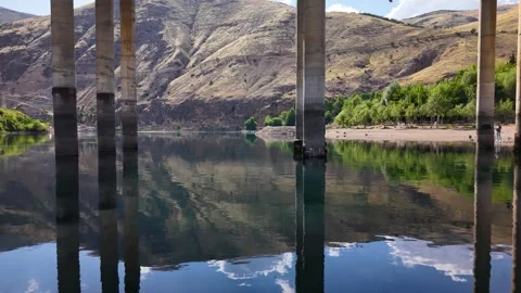 Low Drone Flight Passing Beneath Long Bridge Over Calm Lake Video stock 340235592
