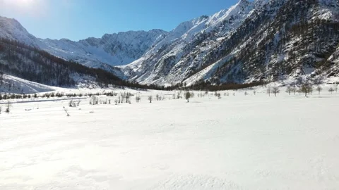 Low drone flight toward the sun in mountain landscape with fresh snow in winter Stock Footage 148031307