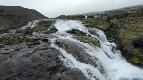 Low drone flyover of cascading waterfall over rocks near Reydarfjordur Stock Footage 346552240