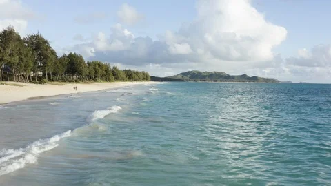 Low drone reverse flight over sea waves and yellow sand beach along coast Hawaii Stock Footage 126604910