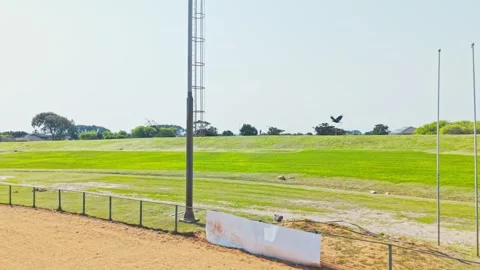 Low Drone Shot of Empty Sports Field With Flagpoles, Stadium Lighting Mast and 動画素材 346653937