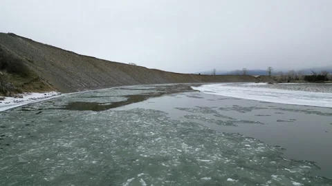 Low drone shot flying downstream over icy river Stock Footage 327703838