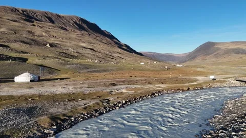 Low drone tracking shot along rushing glacial river stream in valley Stock Footage 348401557