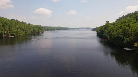 Low drone view of Baptist Lake surrounded by green forest and vacation cott.. Stock Footage 315592404