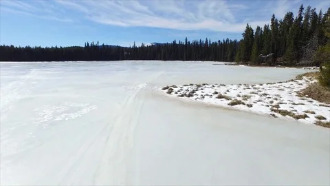 Low elevation aerial flight over frozen lake to reveal forest Stock Footage 72546946