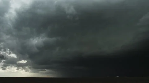 Low fast-moving thunderstorm rolls across prairie as headlights speed by at Stock Footage 59525561