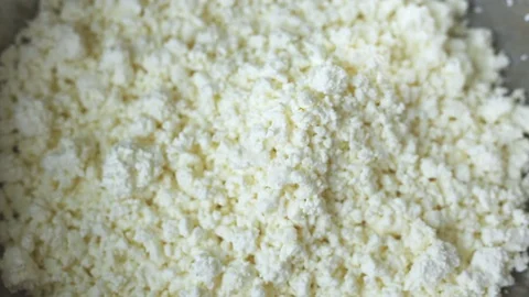 Low-fat, useful from cow's milk, white crumbly curd is poured from above into an Stock Footage 103568506
