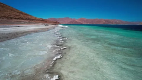 Low flight along icy shallows beside Yamdrok Lake shore Stock-Footage 345885735