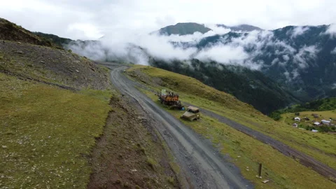 Low flight over a curvy dirty road towards the cloudy mountains Video stock 229868416