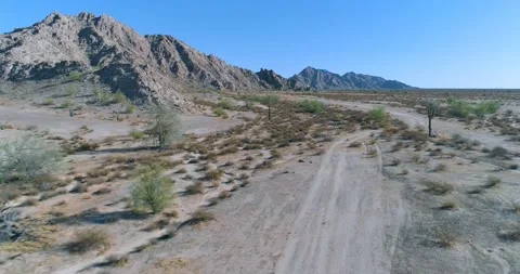 Low flight over dirt trail road flanked by saguaro cactus along rocky hill i Stock Footage 147242647