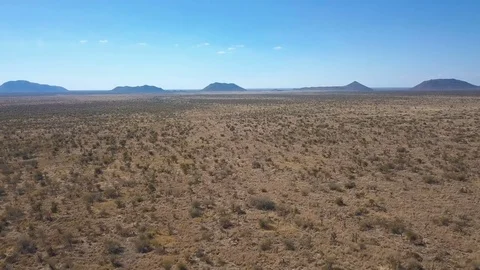 Low flight over dry scrub with blue hills on the horizon Stock Footage 80599185