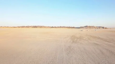 Low flight over the edge of island on salt pan rising to reveal landscape Stock Footage 80596954