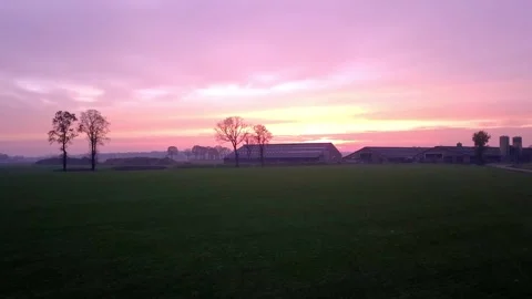 Low Flight Over Farmfield to Farm Under Purple Sunset Stock Footage 256010659