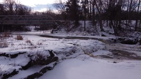 Low flight over frozen river revealing waterfall and gorge Stock Footage 228469831