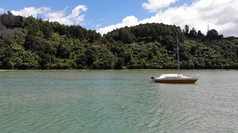 Low flight over a lagoon, past a yacht and toward the tree-line Video stock 100689158