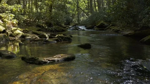 A low flight over a mountain stream toward a small cascade. Stock Footage 116413673