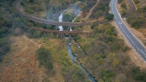 Low flight over small river with rail tracks crossing burnt valley Stock Footage 78584588