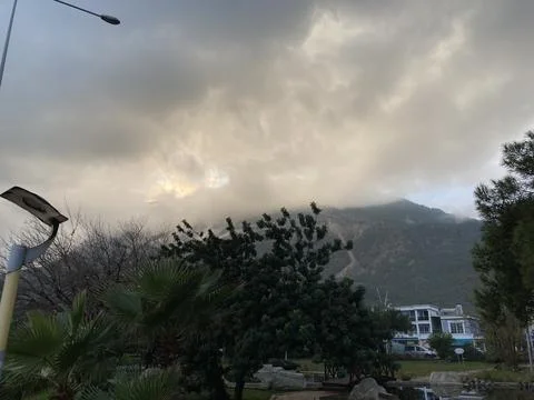 Low fluffy clouds hang over the high mountains, cover their peaks Stock Photos