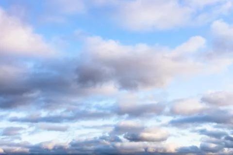 Low fluffy gray clouds in blue sky in twilight Stock Photos