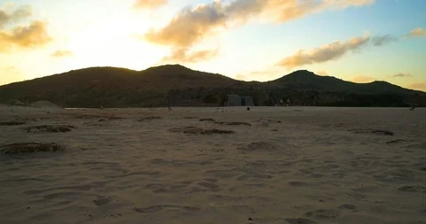 Low fly over beach sand with sunset behind hills in frame Stock-Footage 97768635