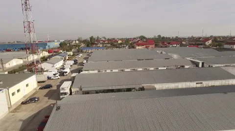 Low flying aerial perspective over industrial warehouses. Video stock 61823931