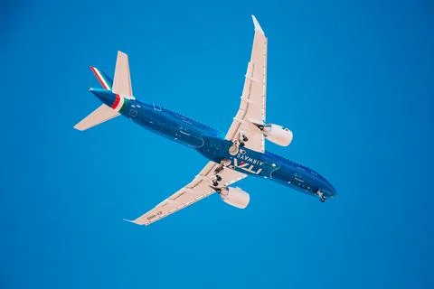 Low flying blue plane with white wings Airplane landing. Airplane on a blue Stock Photos
