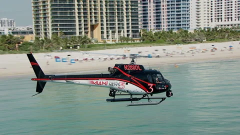 Low flying pull out on helicopter above waves of Miami beach Stock Footage 136199601