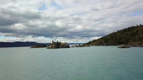 Low flying shot over lake approaching rock. Stock Footage 115509357