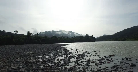 Low flyover of pebbled beach, river and rain forest in Papua New Guinea, 4k Stock Footage 123522325