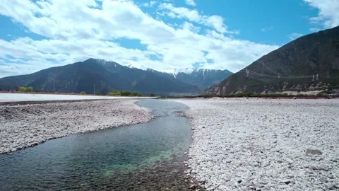 Low forward aerial along a shallow rocky river channel in Tibet Stock-Footage 345884291