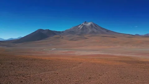 Low forward flight over vast red arid desert plain approaching a dramatic Stock Footage 336266011