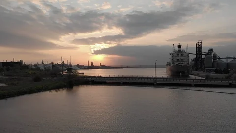 Low forward move over water into an industrial harbour at sunset Video stock 112633908